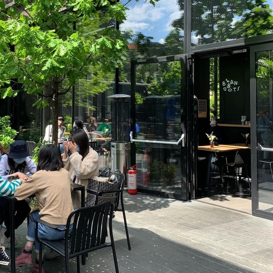 oameni iau masa pe terasa la Beans & Dots.