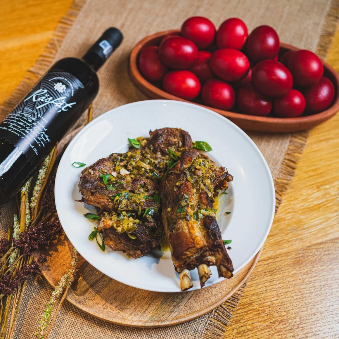 friptura de miel alaturi de un platou cu oua rosii si o sticla de vin. Restaurante La Mama comandă masa de Paște