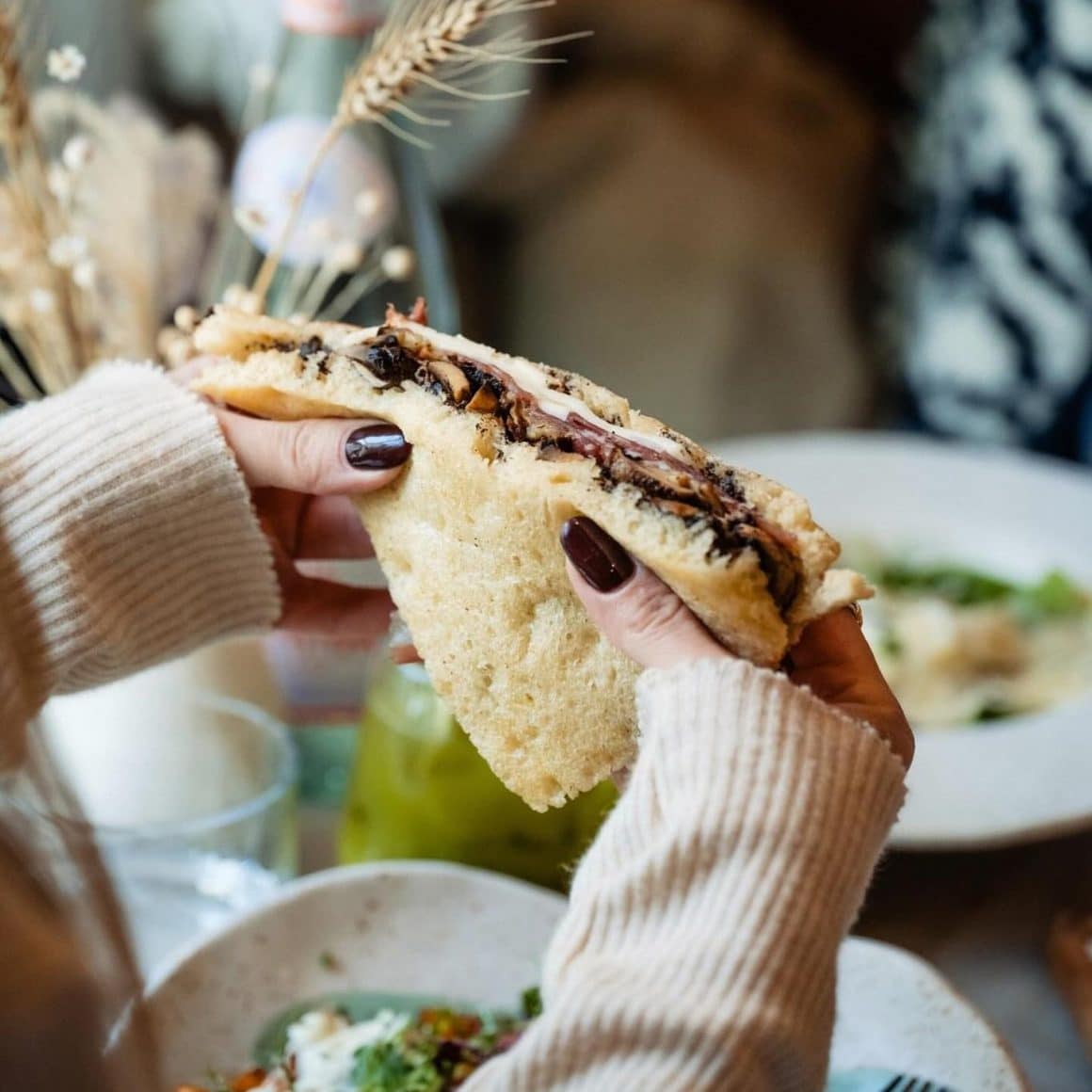 close up cu un panini cu trufe de la Mano Bocca, tinut in maini de o femie. Sandwich București