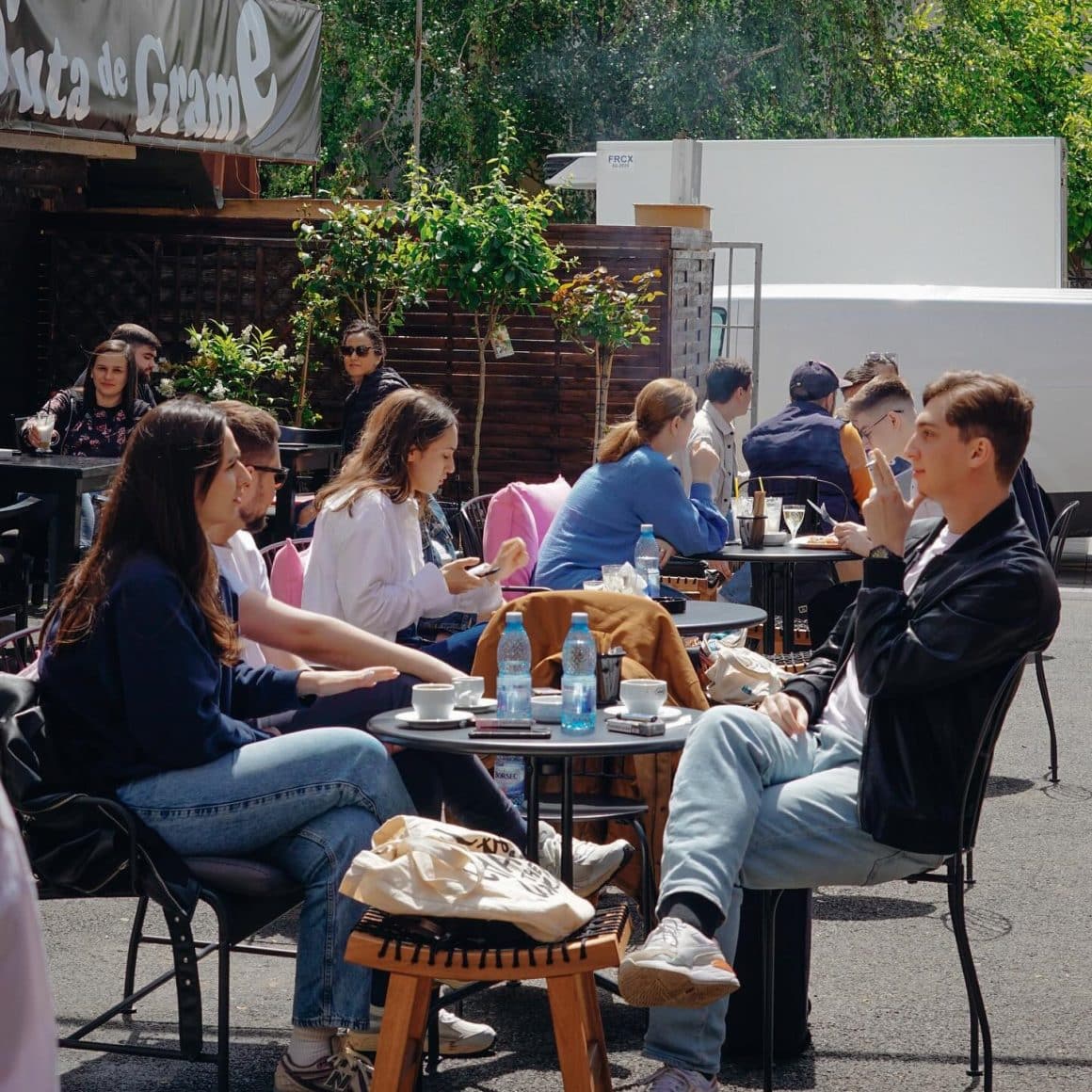 mai multi oameni iau masa pe terasa afara la Suta de Grame, loc cu panini în București