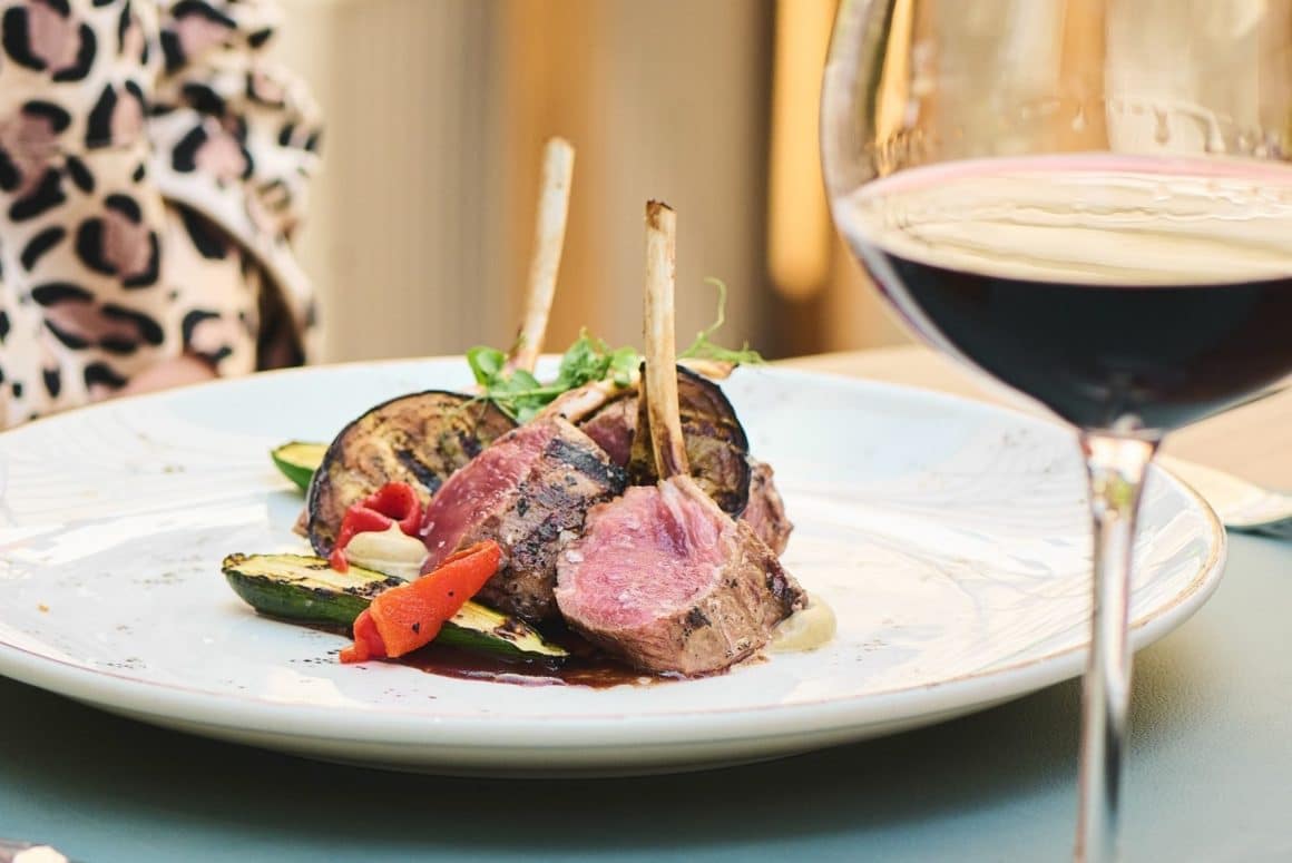 cotlete de miel servite elegant alaturi de un pahar de vin rosu