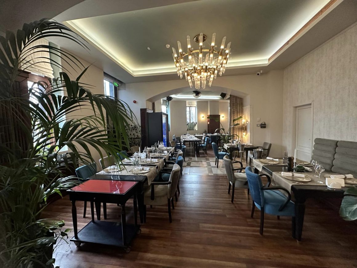 Restaurant Merlot din Timișoara, amenajat elegant, cu un candelabru mare in mijlocul incaperii