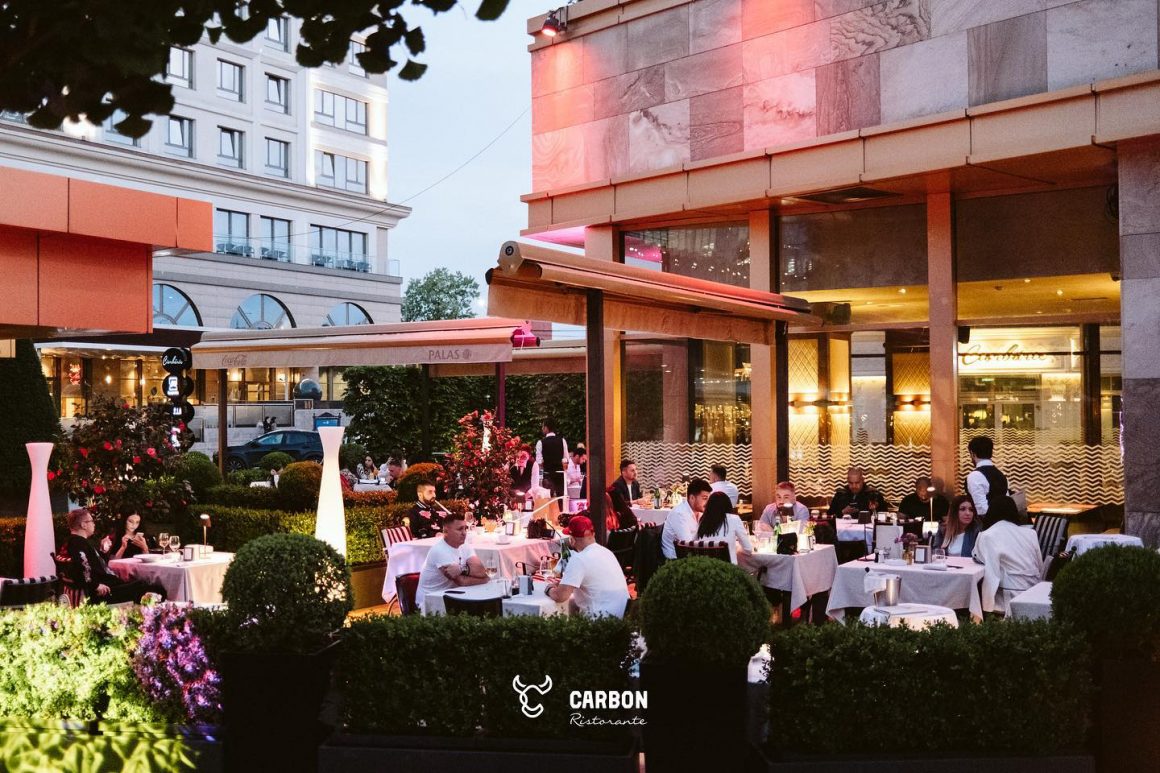 mai multi oameni iau masa pe terasa la restaurant carbon. restaurante Iași