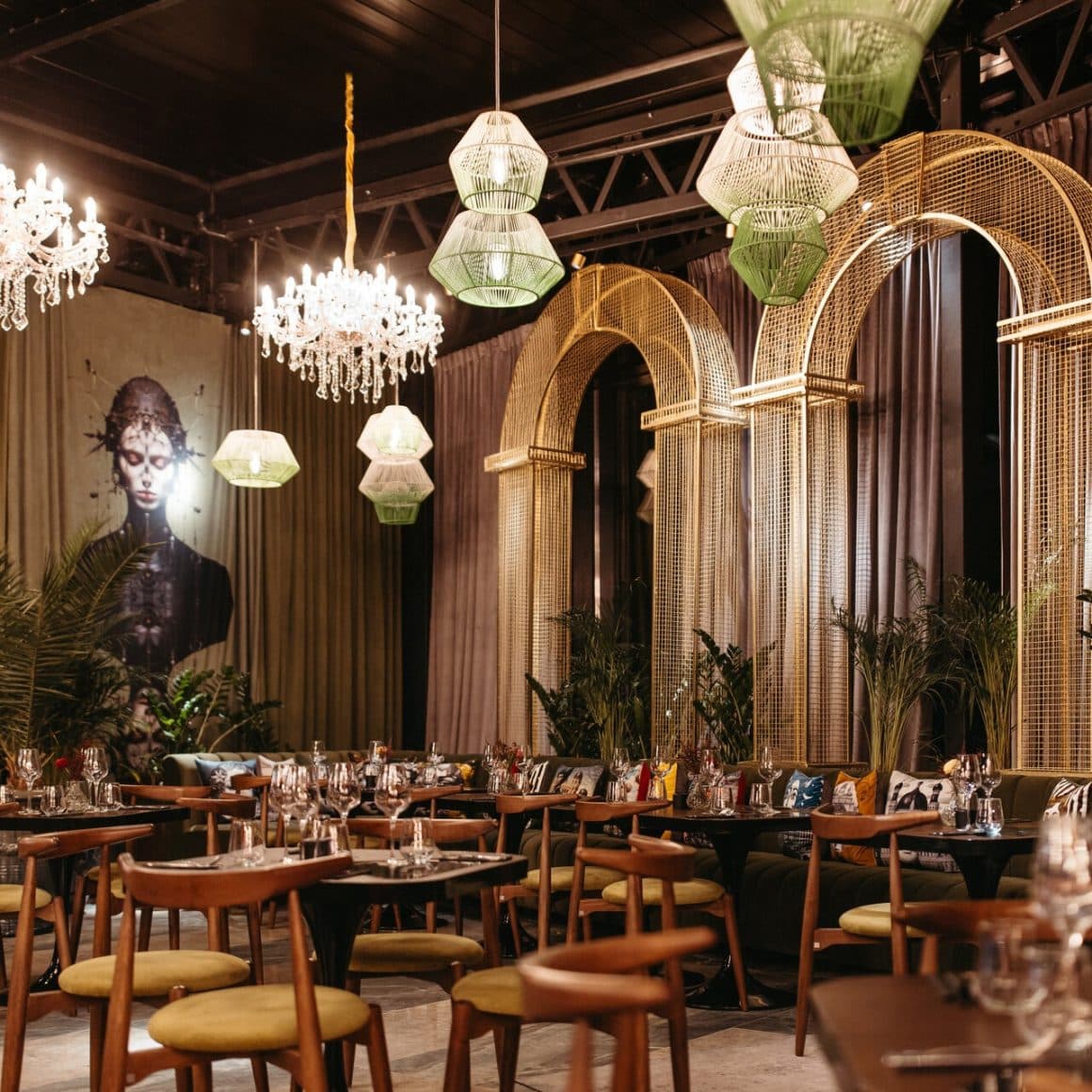 interiorul restaurantului Nuba Palace, decorat cu candelabre luxoase, arcade aurii, un perete cu pictura murala si mobilier elegant. Restaurante din Iași