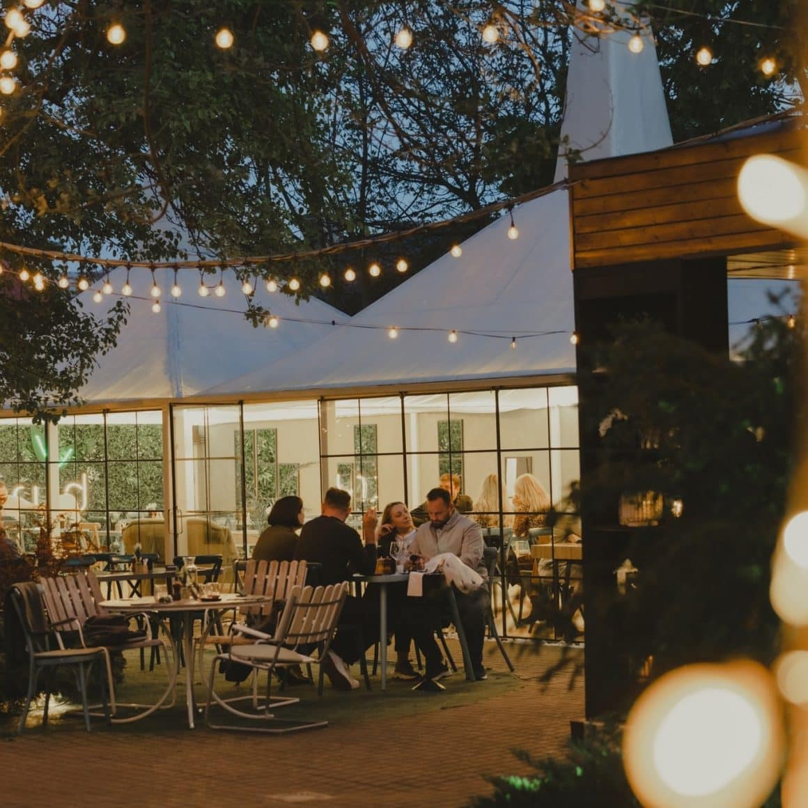 mai multi oameni iau cina pe terasa la Krud. restaurante Iași