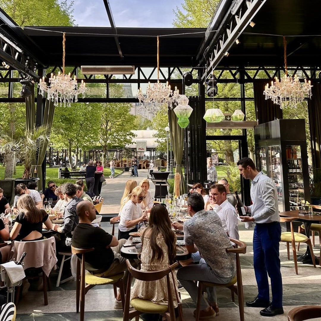 mai multi oameni iau masa pe terasa de la Nuba Palace, cu vedere spre parc