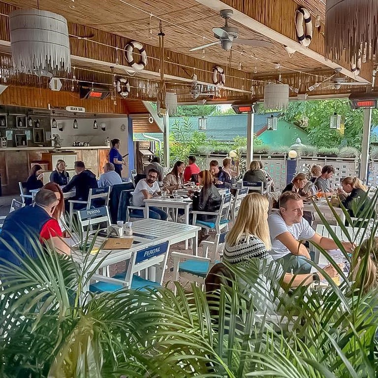 terasa restaurantului Blue Aqua din Iași, amenajata pescaresc, plina de oameni care iau masa