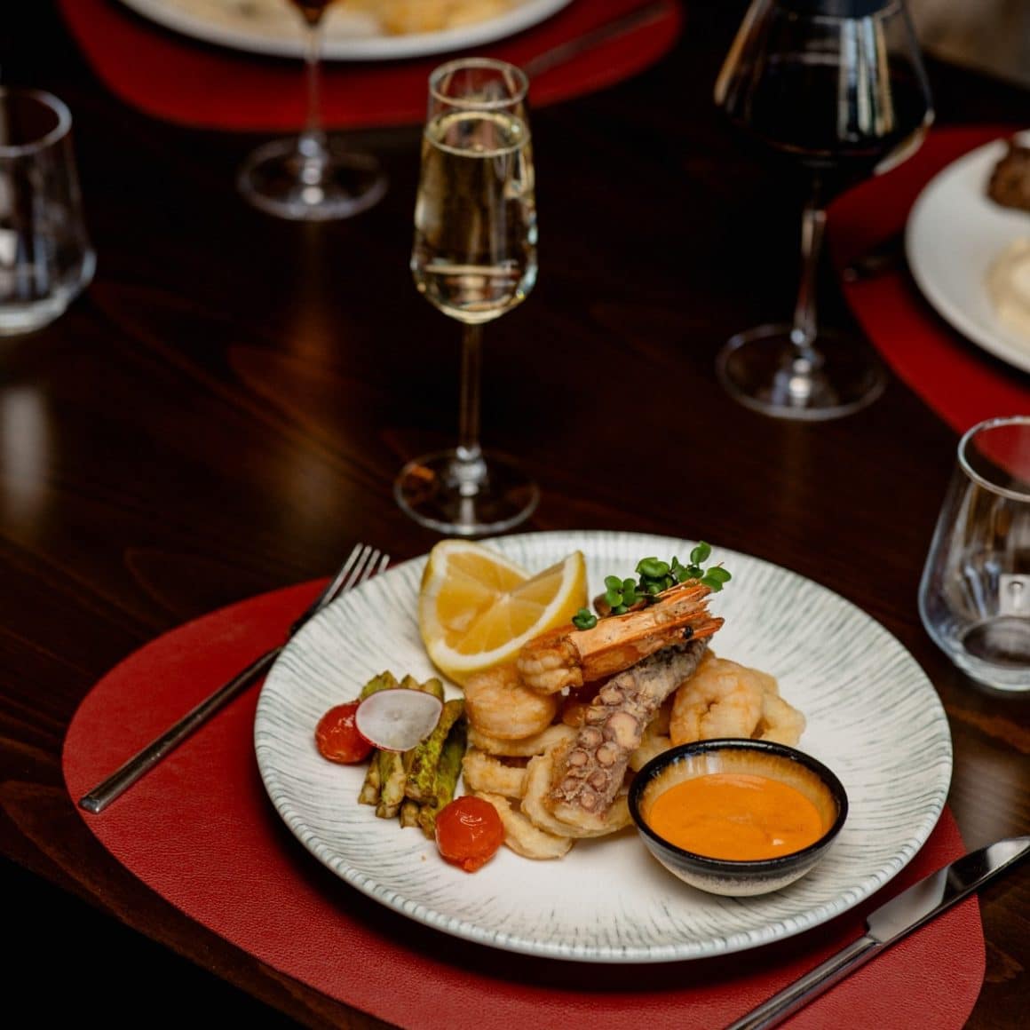 mix de fructe de mare, servite cu sos alaturi de un pahar de vin alb