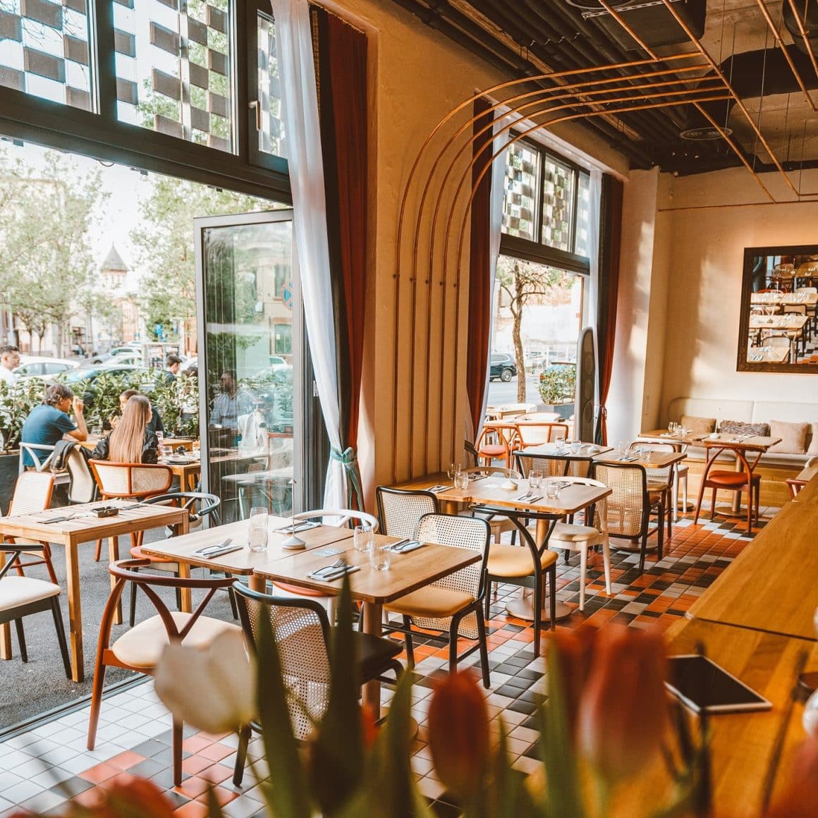 Imagine din interiorul restaurantului Nishani, cu ferestre mari, deschise, care dau afara pe terasa