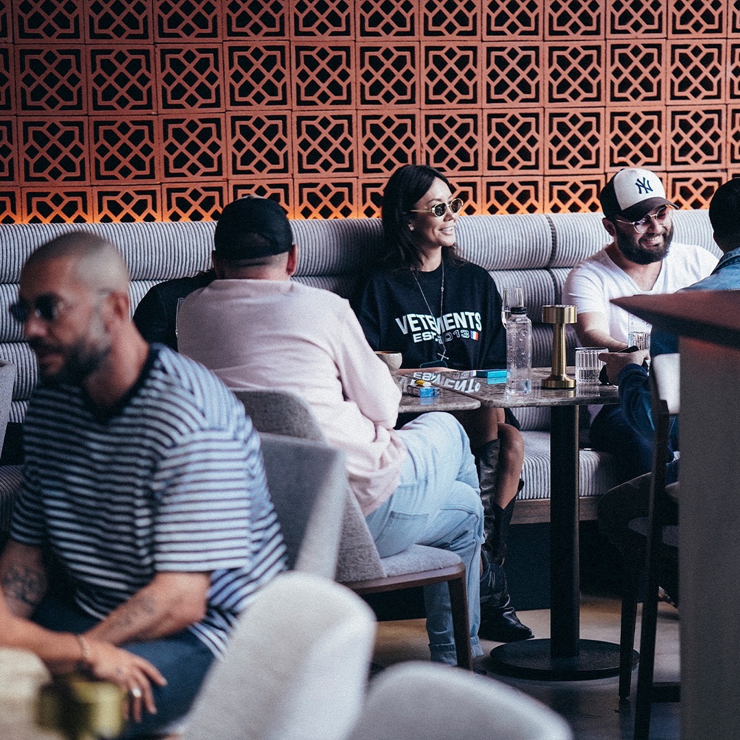 grup de prieteni ia masa la Matinee Floreasca, relaxati pe o canapea, in fata mesei. Locuri noi București