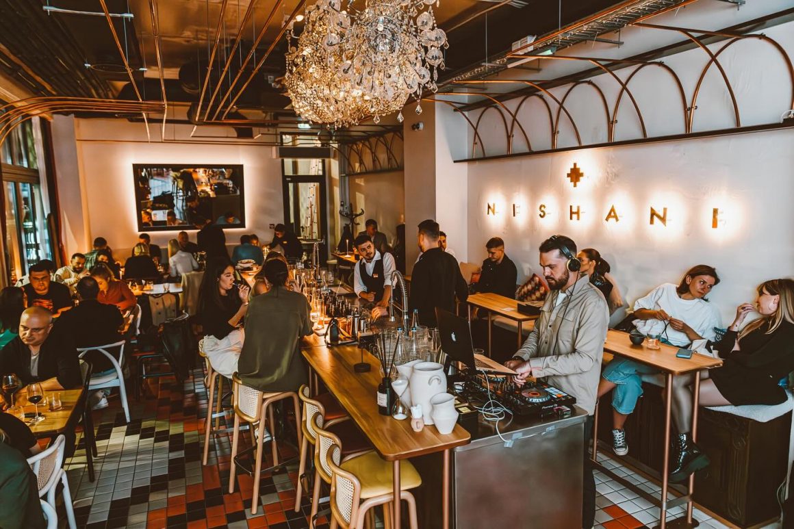 Mai multi oameni iau masa in restaurant Nishani, seara. Restaurant cu candelabre. Nishani. Locuri noi București