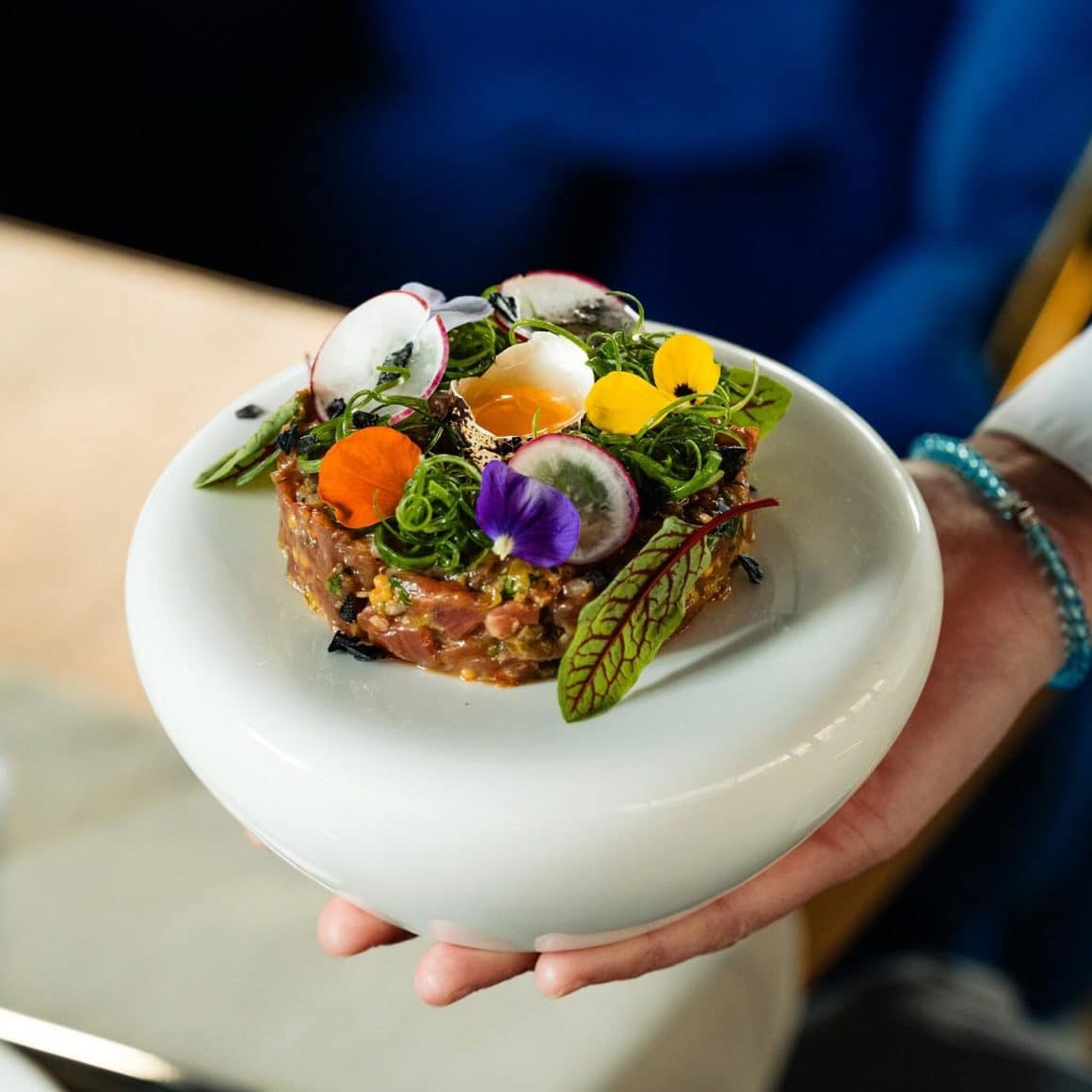 clos eup cu o farfurie de fine dining, cu tartar decorat cu legume si flori comestibile