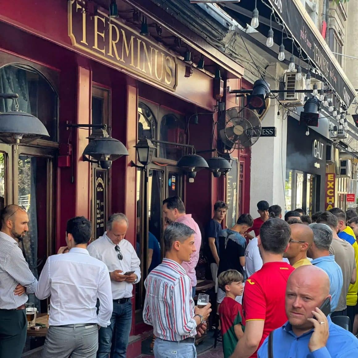mai multi barbati adunati in fata la terminus pub din Bucuresti, stau de vorba