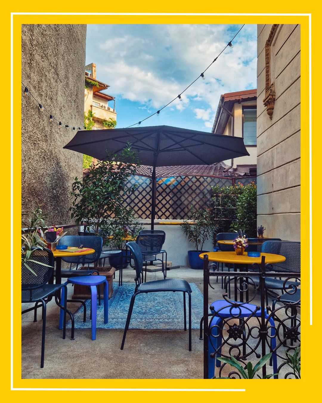 terasa de la restaurantul mosafir, cu mese galbene, rotunde, si scaune albastre