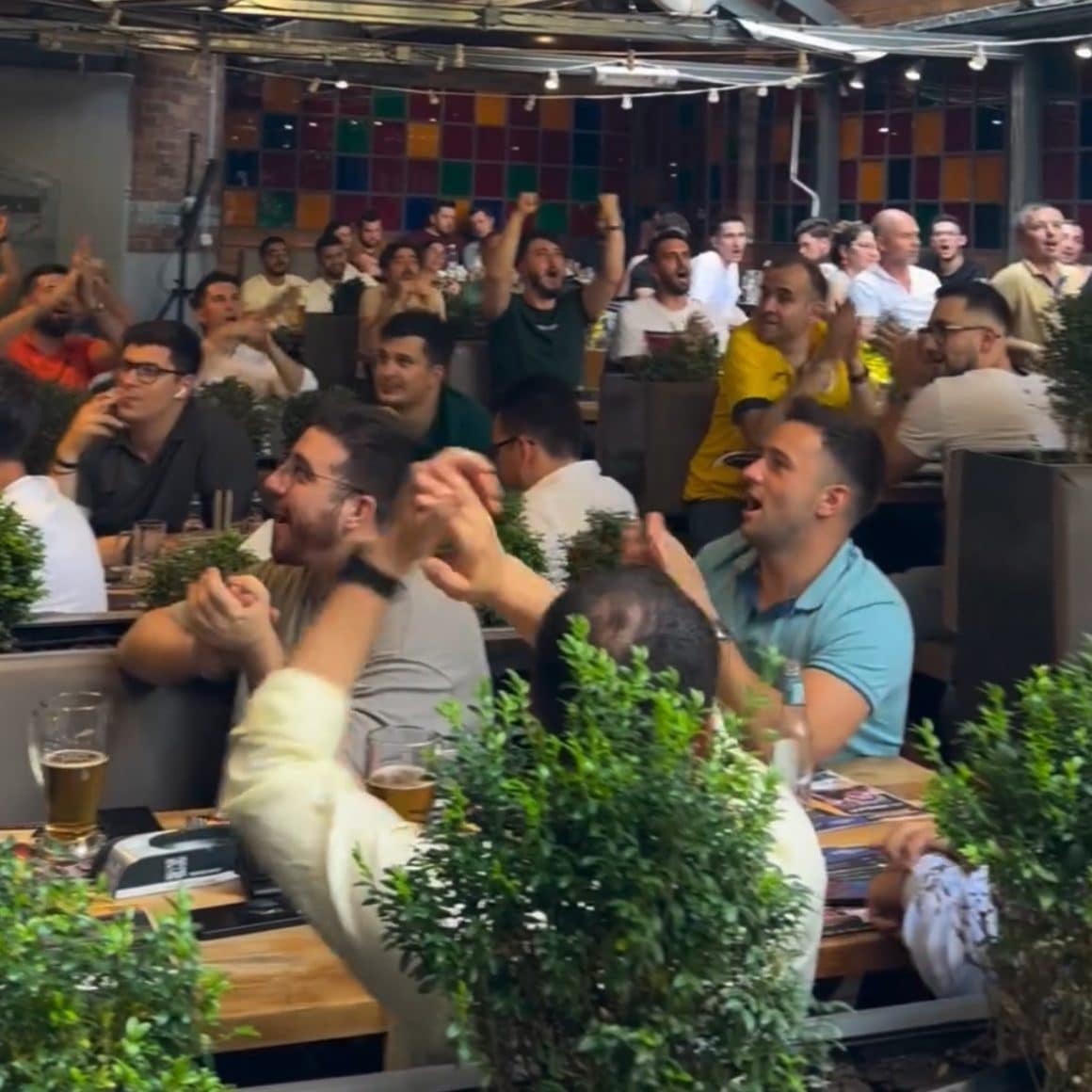 mai multi oameni la terasa la Curtea Berarilor s ebucura dupa ce echipa de fotbal a dat un gol. Terase și baruri sportive București.