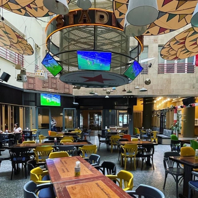sala de mese de la restaurant Stadio, cu atrium, unde sunt suspendate ecrane TV la care poti urmari meciurile in București. terase și baruri sportive București