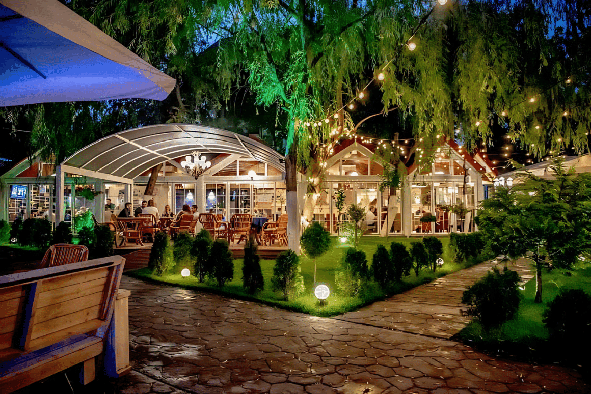 terasa mare, cu alei pline de verdeata, oameni care stau la mese seara, si lumini in copaci, la Blue Aqua, unul din rerstaurante bune din Iași