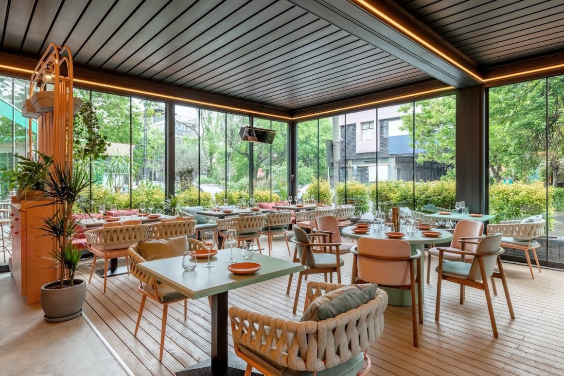 terasa spatioasă, aerisita, de la Mezeya, cu mese patrate si rotunde, amenajata in nuante de crem, verde mentă si roz. Locuri noi București