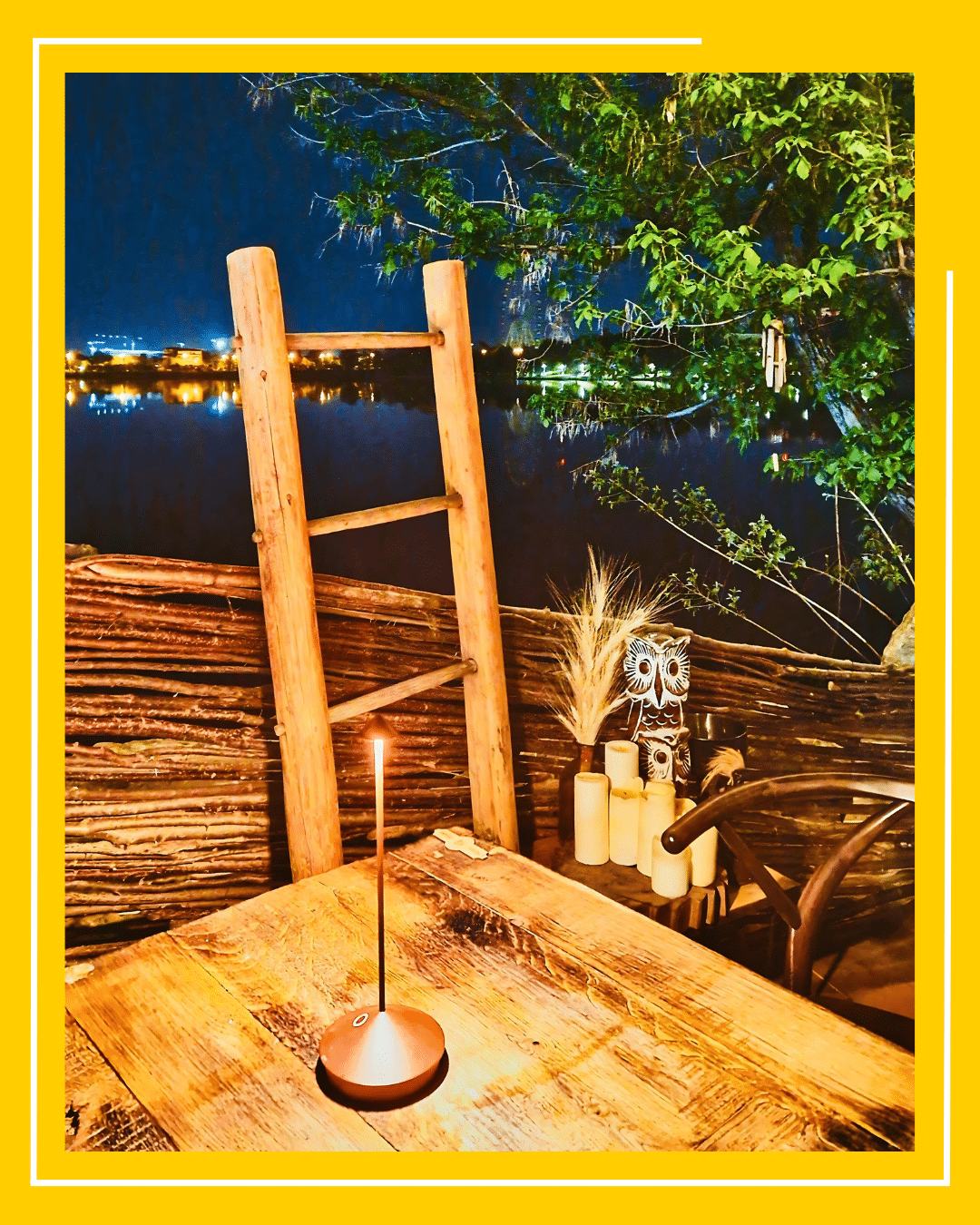 terasa de la Indigen Space for the Soul București, fotografiata seara, pe malul lacului, cu mese de lemn si luminite in copaci