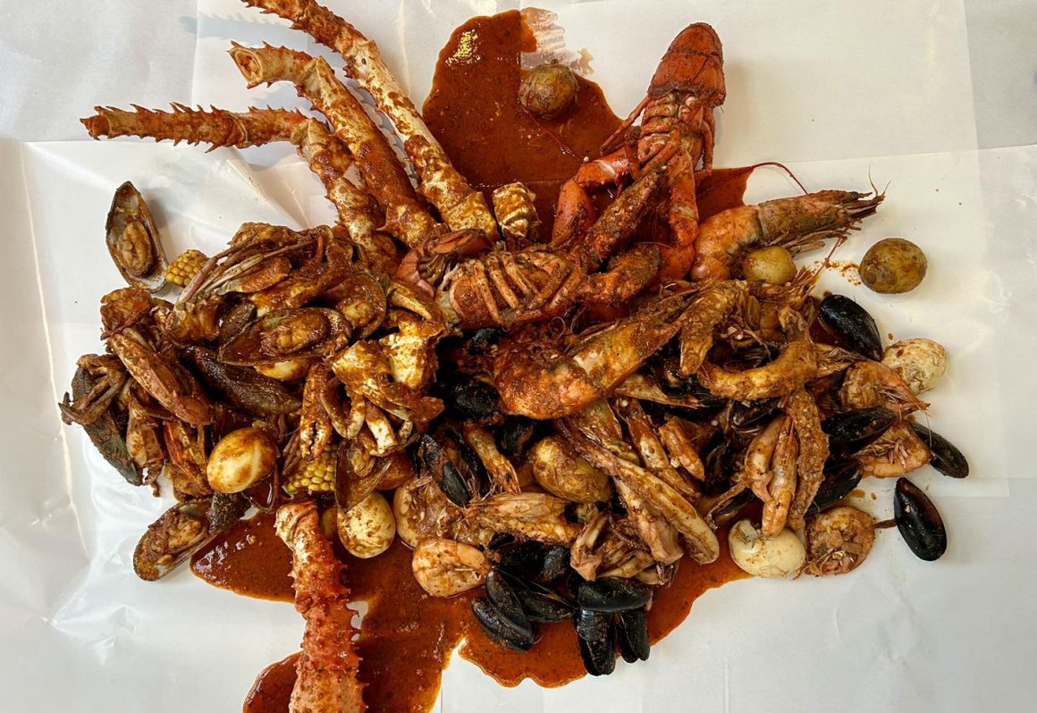 seafood boil în sos cajun. Este un mix de fructe de mare (creveți, scoici, midii, calamar, crab), cartofi, ouă și porumb îmbibate într-un sos din condimente cajun și servit cu o garnitură de orez. De la JUicy Crab. Restaurante cu fructe de mare București.