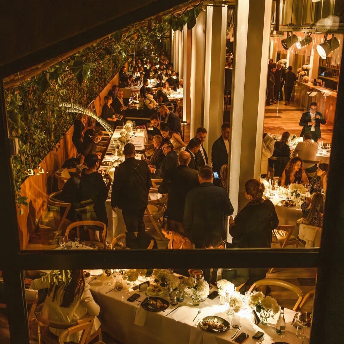 mai multi oameni iau masa la Linea Closer to the moon, seara, in spatiul cu candelabre mari si lumina calda, difuza. Oferte de Revelion de la restaurant