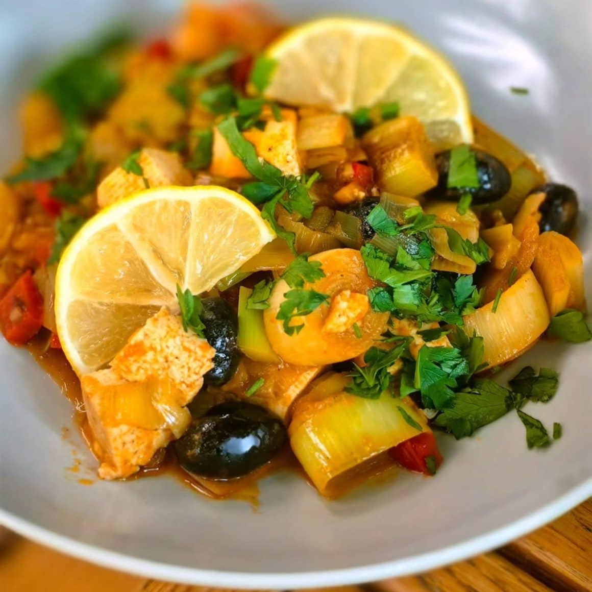 close up cu o mancare cu praz, legume, verdeata si felii de lamaie, de la Nom Nom București