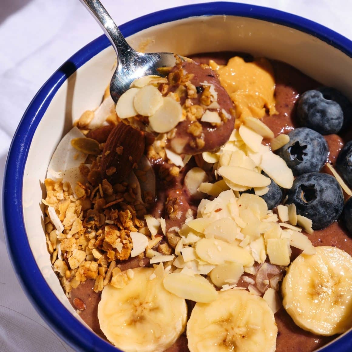 Bol cu iaurt, cacao, felii de banana, afine si fulgi de migdale de la Avocadoo