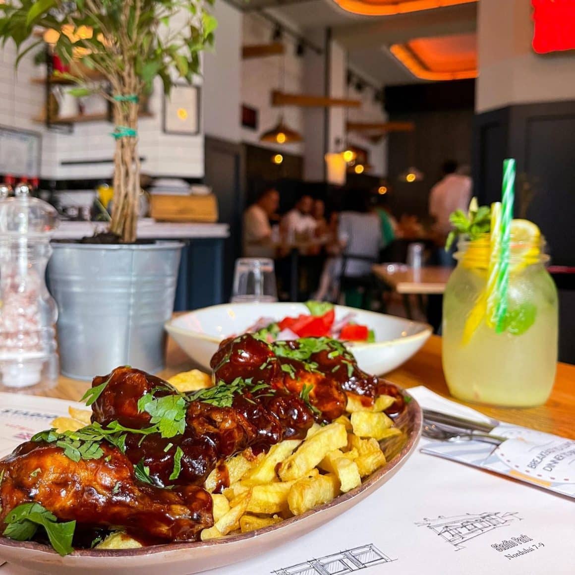 platou cu aripioare picante asezate peste cartofi prajiti, pe masa la restaurant Stadio București