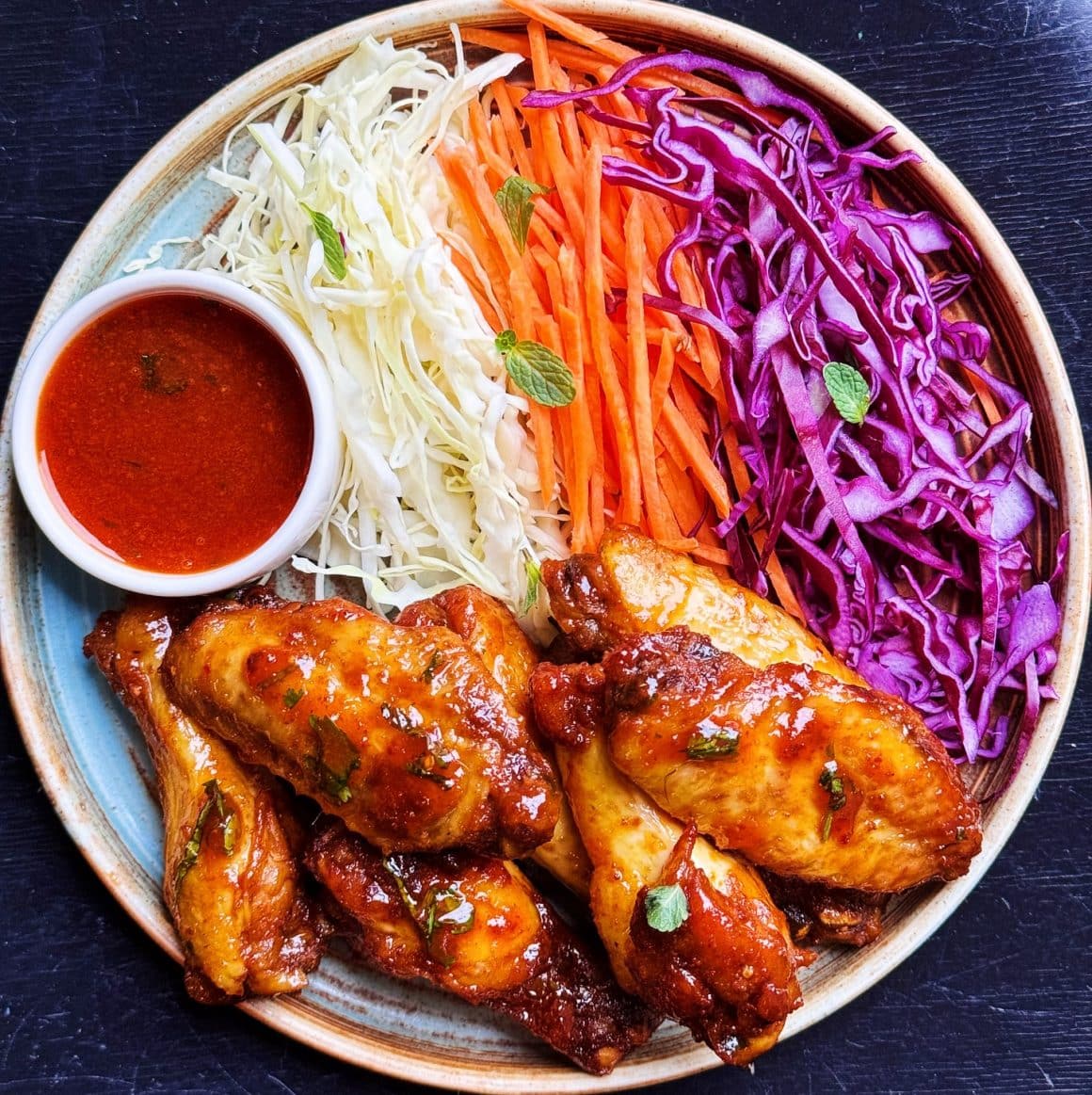Aripioare picante la cuptor în sos de sweet chili, usturoi, ghimbir, soia, lime, chili, sos de pește, coriandru proaspăt. Servite cu varză albă, varză roșie, morcov și extra sos. De la Energiea București