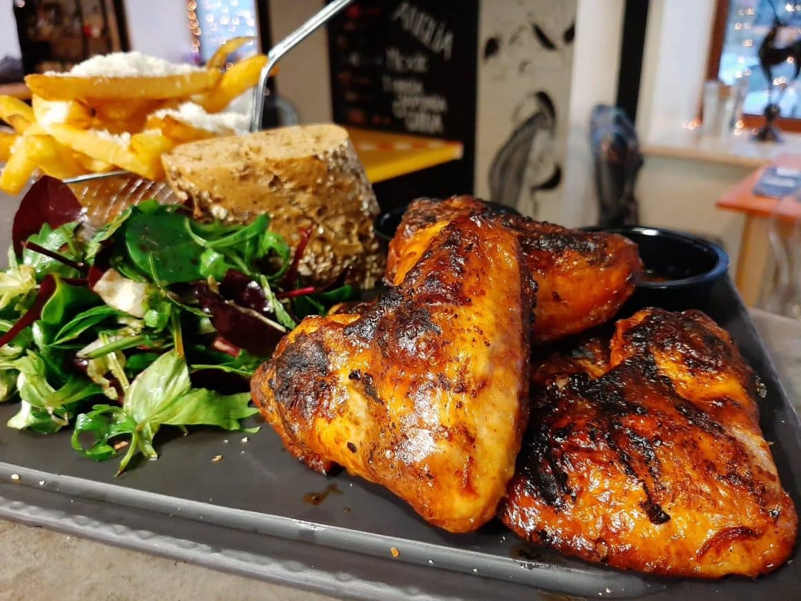 prim plan cu aripioare picante la jar, asezate pe platou negru, langa un cosulet cu cartofi prajiti si doua boluri cu sos iute si sos alb, la Grivița Pub and Grill București