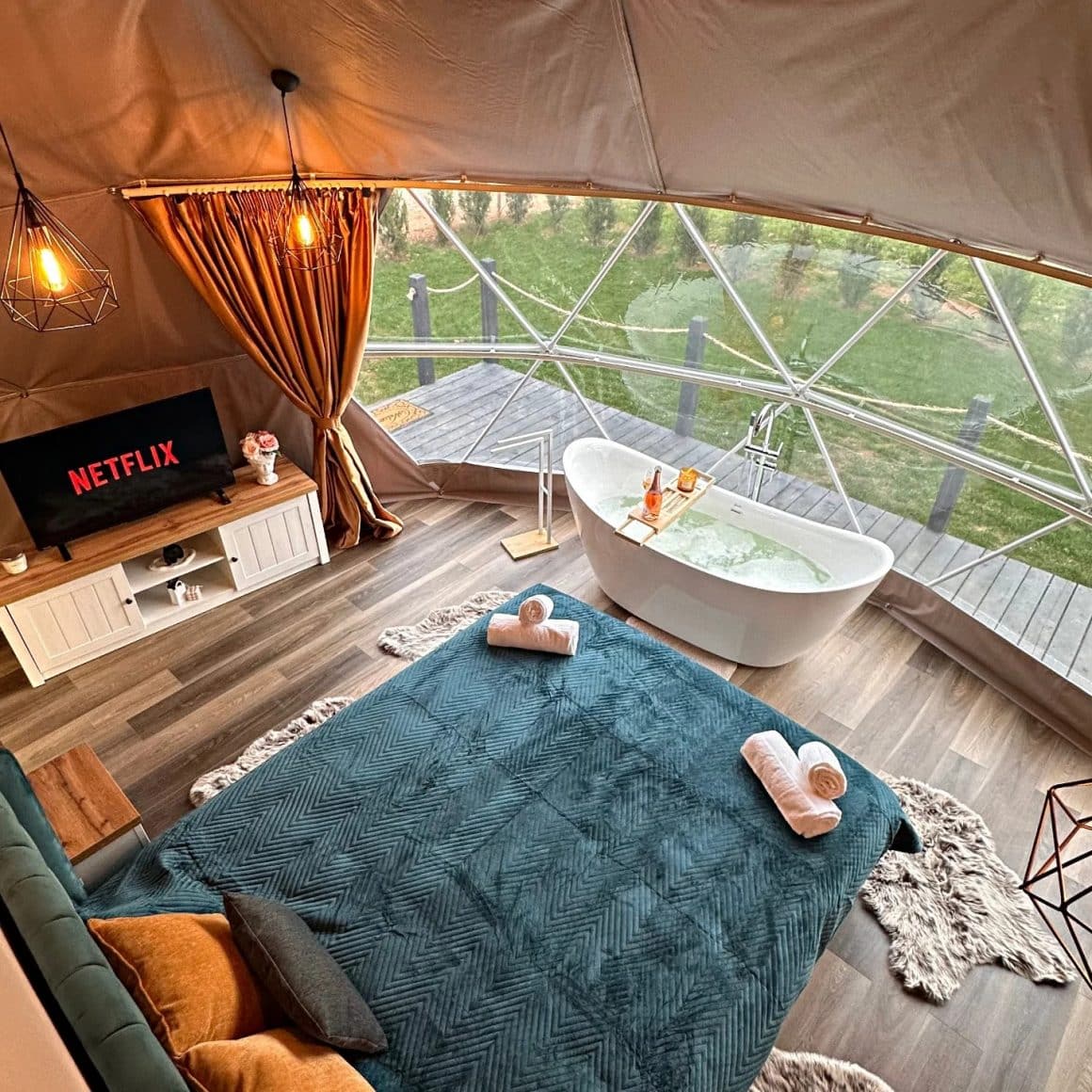 cort de glamping amenajat luxos, cu pat mare si cada freestanding