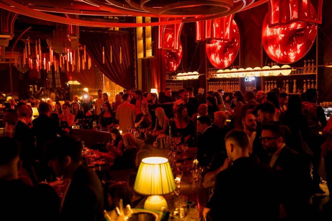 Mai multi oameni petrec seara in decorul elegant de la Nuba, cu lumina difuza, rosie. Restaurante pentru o ieșire cu fetele